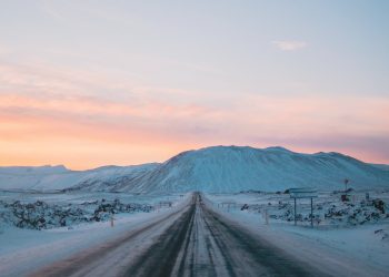 Karlı yol, dağ, pembe bulutlar.