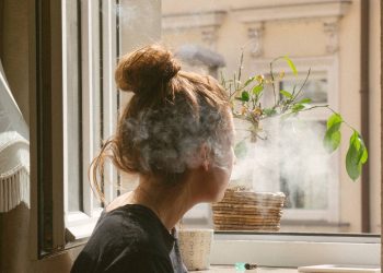 Camda sigara içen genç kız.